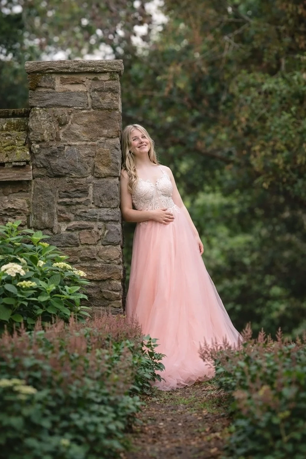 high school senior girl standing near stone wall during natural light senior photography session in South Jersey
