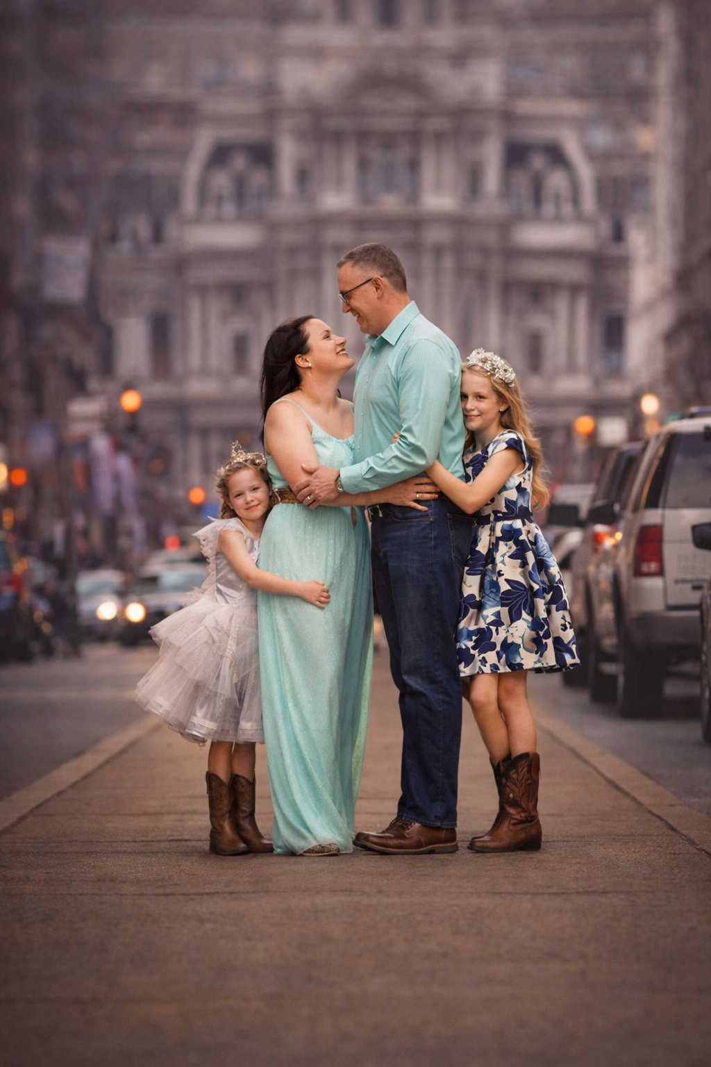 Family portrait photographed in Philadelphia at twilight, showing parents and children sharing a natural, connected moment with City Hall in the background