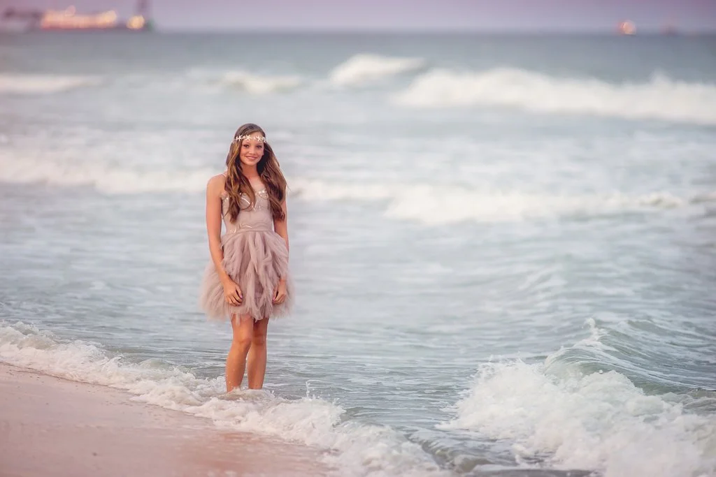 Smiling young girl wearing a flowing dress during a South Jersey beach family photography session, standing in the ocean at the Jersey Shore