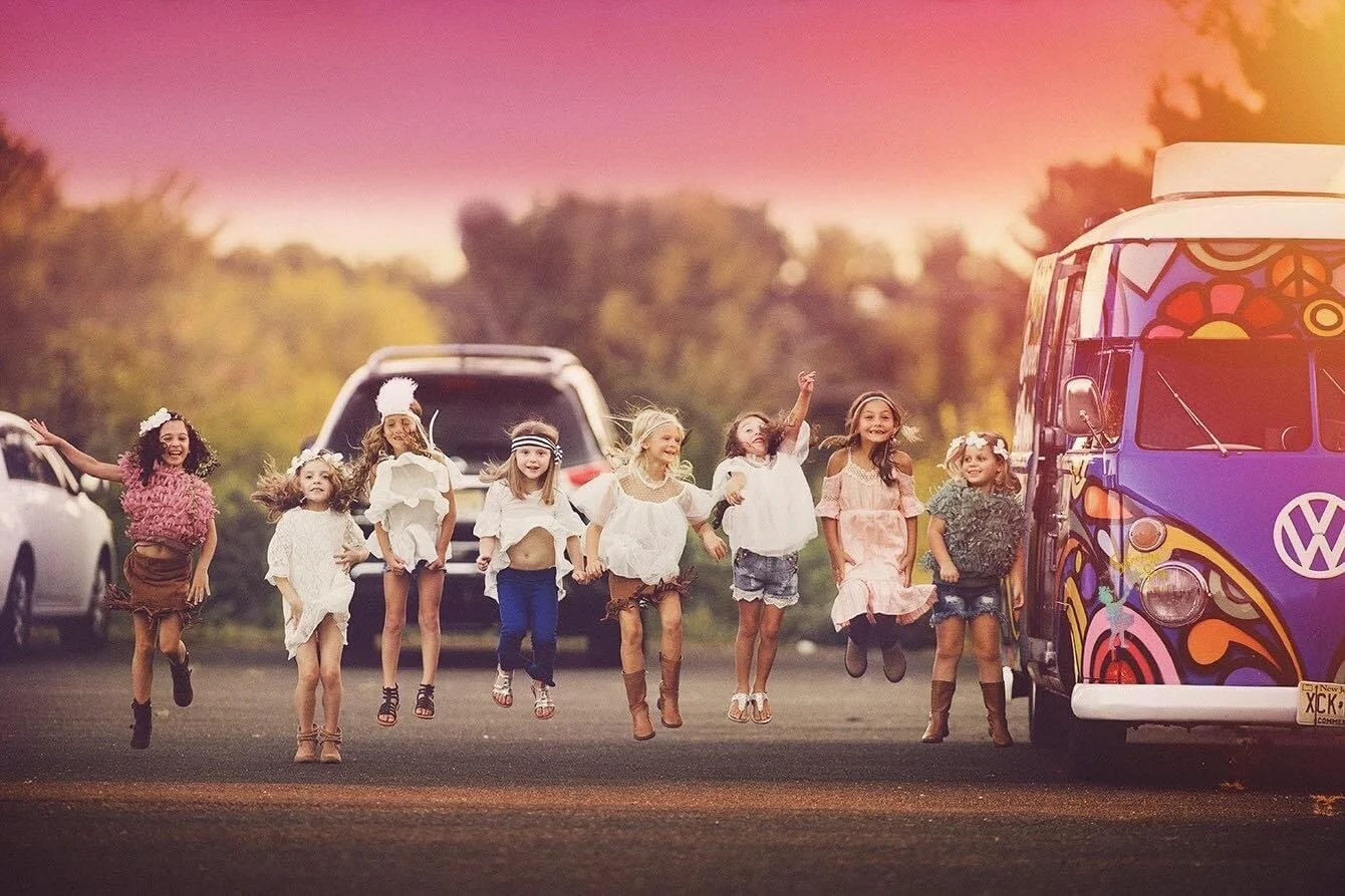 Group of girls jumping and laughing together beside a vintage VW bus during a joyful photo session in South Jersey