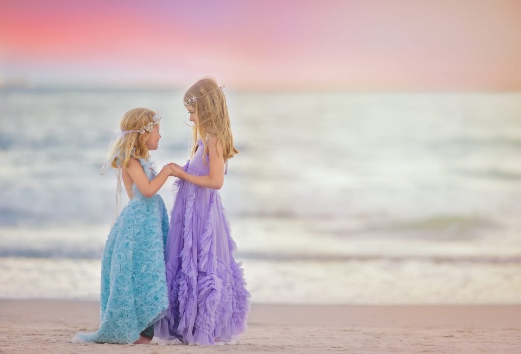 Two sisters holding hands while walking together on the beach during a portrait session in Ocean City, New Jersey along the Jersey Shore.