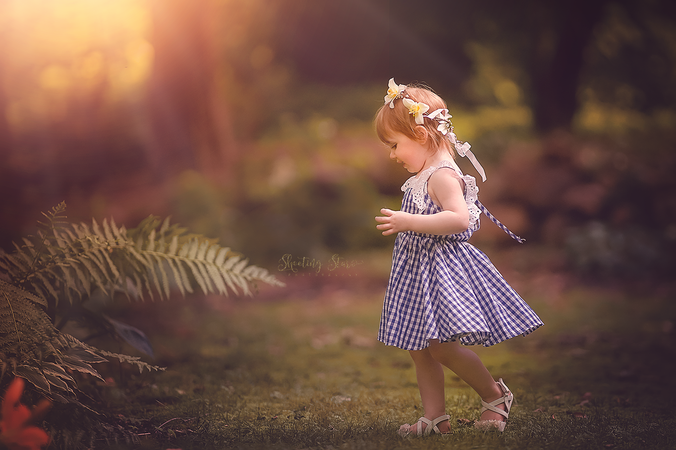 Toddler exploring a sunlit field during a gentle, child-led fine art portrait session in South Jersey, capturing a quiet, natural moment.