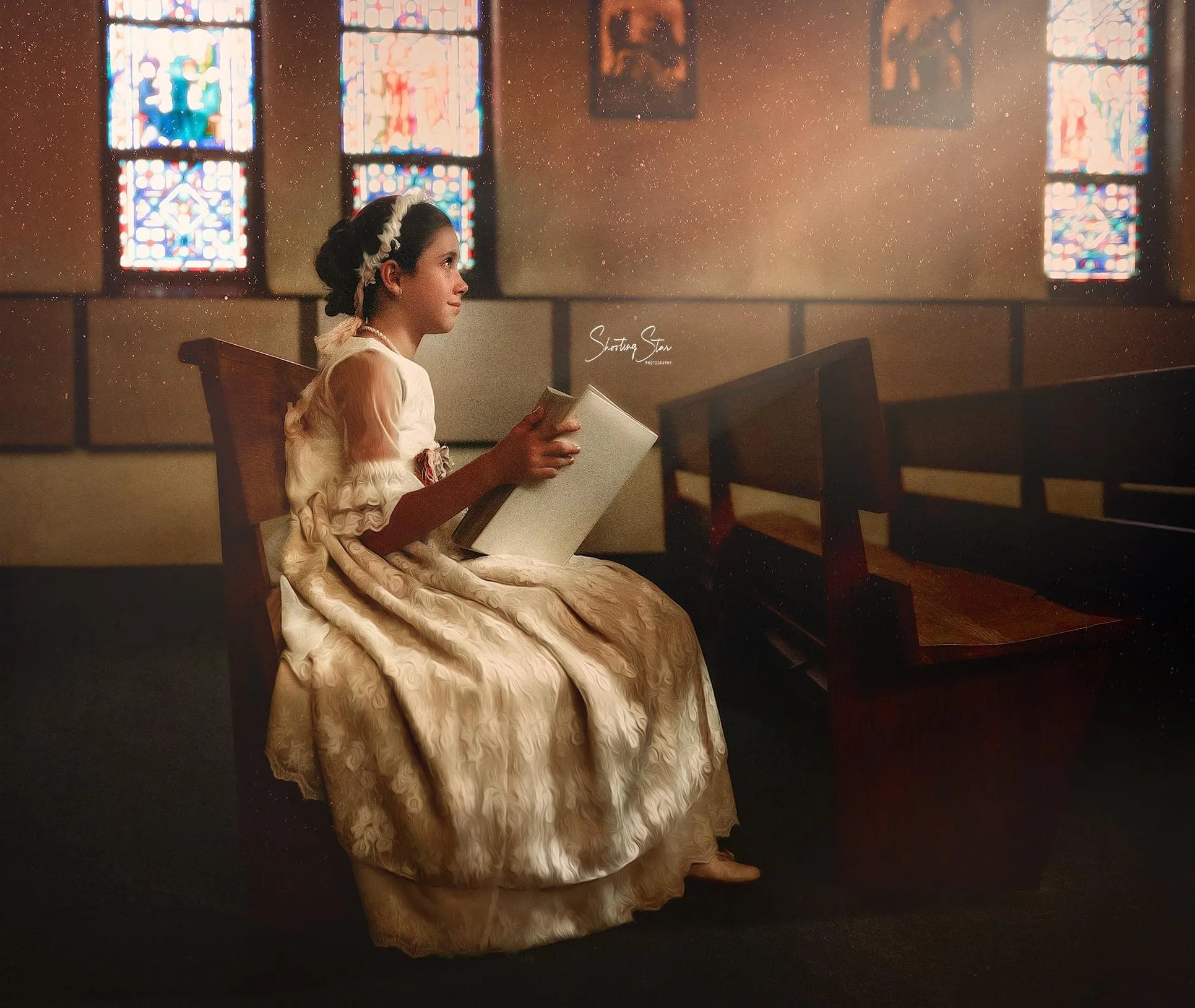 First Holy Communion portrait of a young girl sitting in a church pew reading a Bible during her Communion session