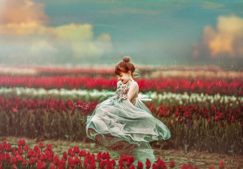 Girl in a gray dress laughing and twirling in a tulip field in New Jersey during a spring portrait session