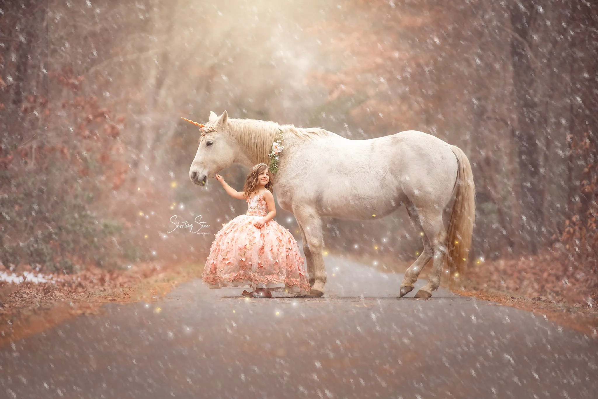 A young girl standing with Drifter the unicorn during a winter unicorn photography session, surrounded by softly falling snow.