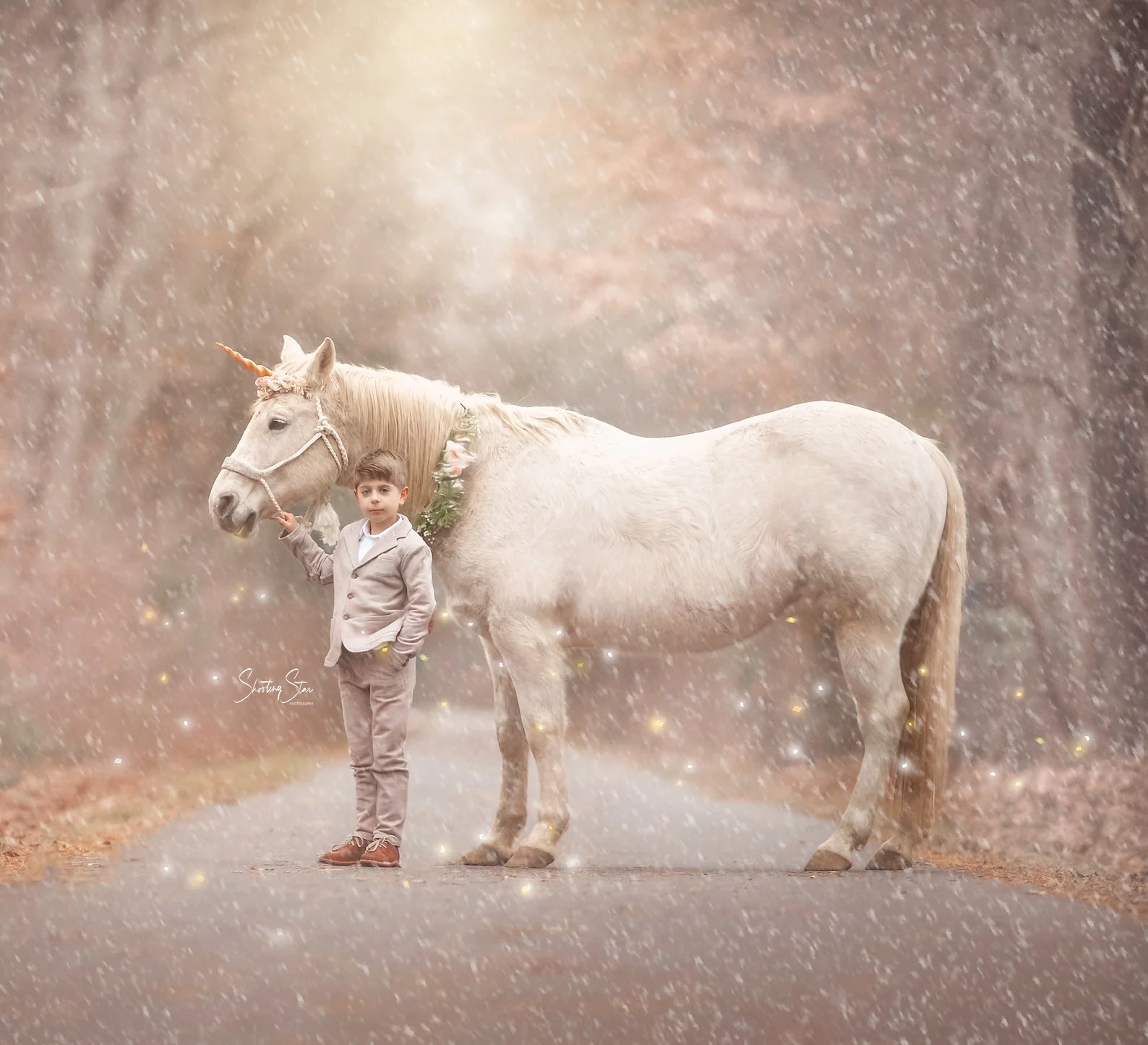 A young boy posing confidently beside Drifter the unicorn during a winter unicorn photography session in the snow.