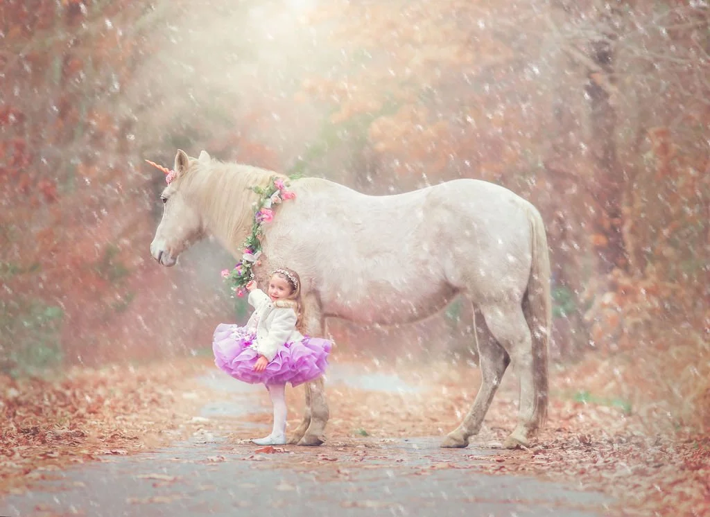 young girl in pink couture dress smiling beside the unicorn Drifter during a fairytale portrait session