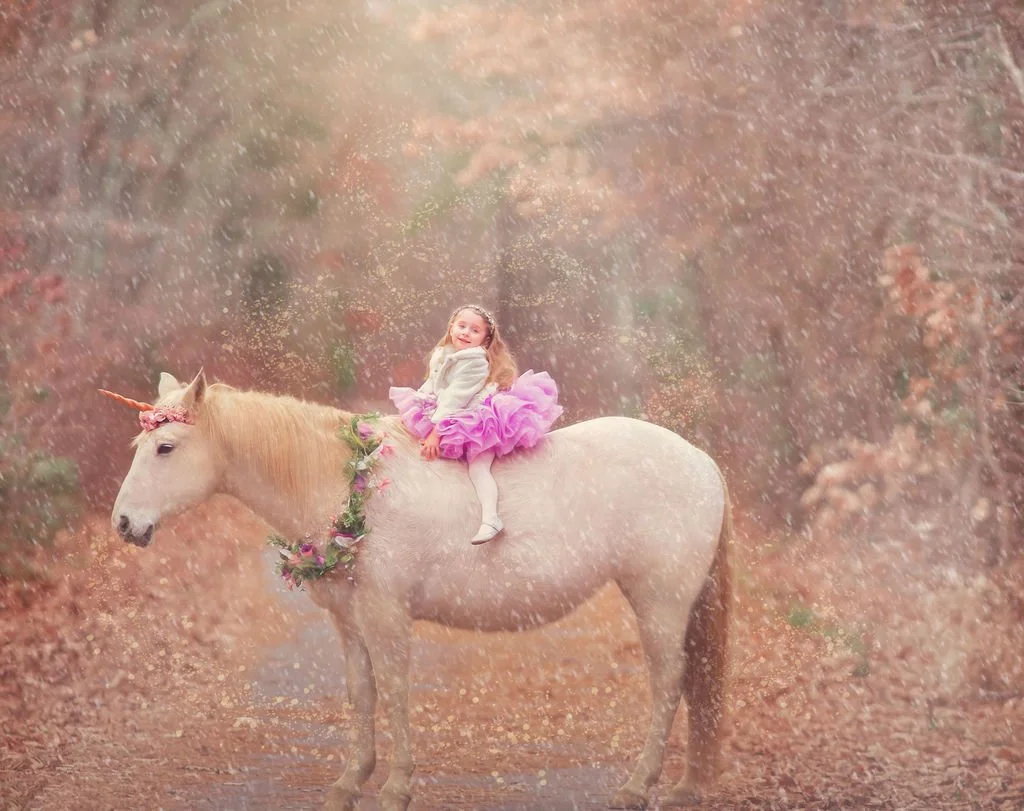 young girl smiling while sitting on the unicorn Drifter during a magical portrait session in New Jersey