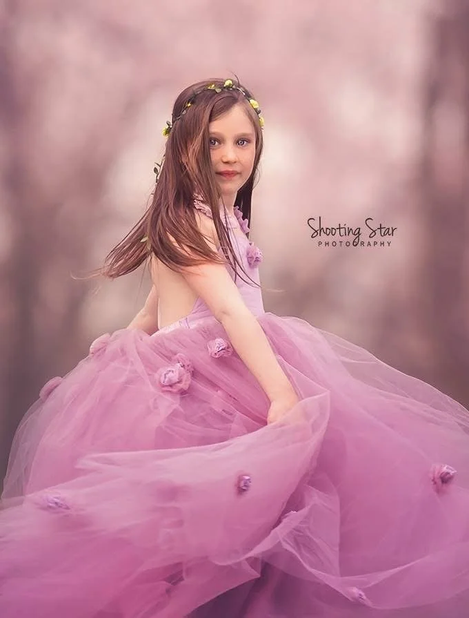 Little girl twirling beneath cherry blossoms during a spring portrait session in Cherry Hill, New Jersey.