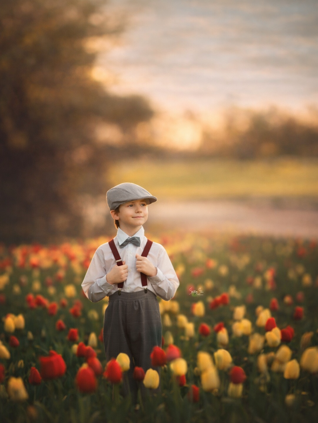 A young boy in a vintage outfit standing among tulips, photographed in soft natural light for a timeless fine art children’s portrait.
