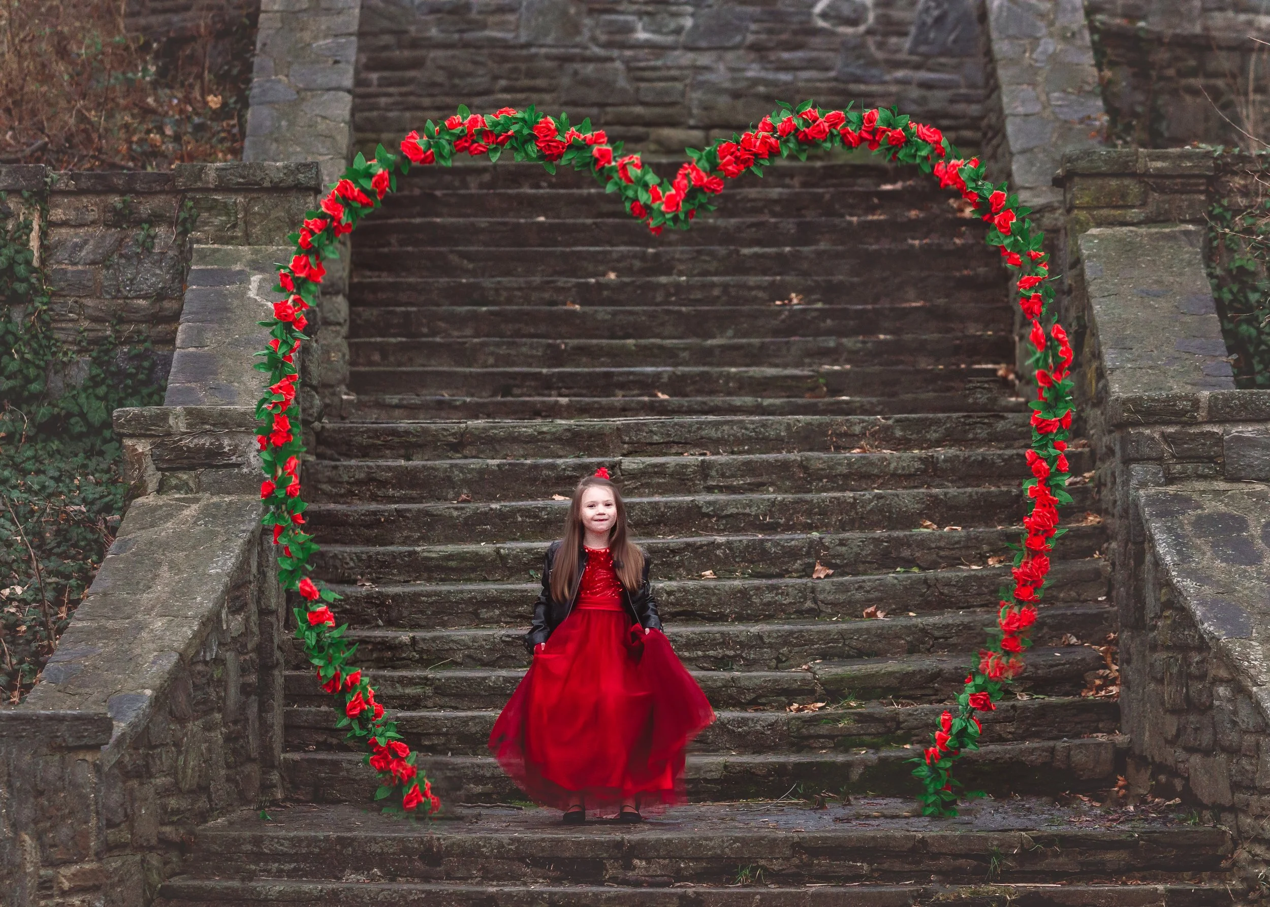 Smiling little girl in a red dress during a Valentine’s Day portrait session in New Jersey.