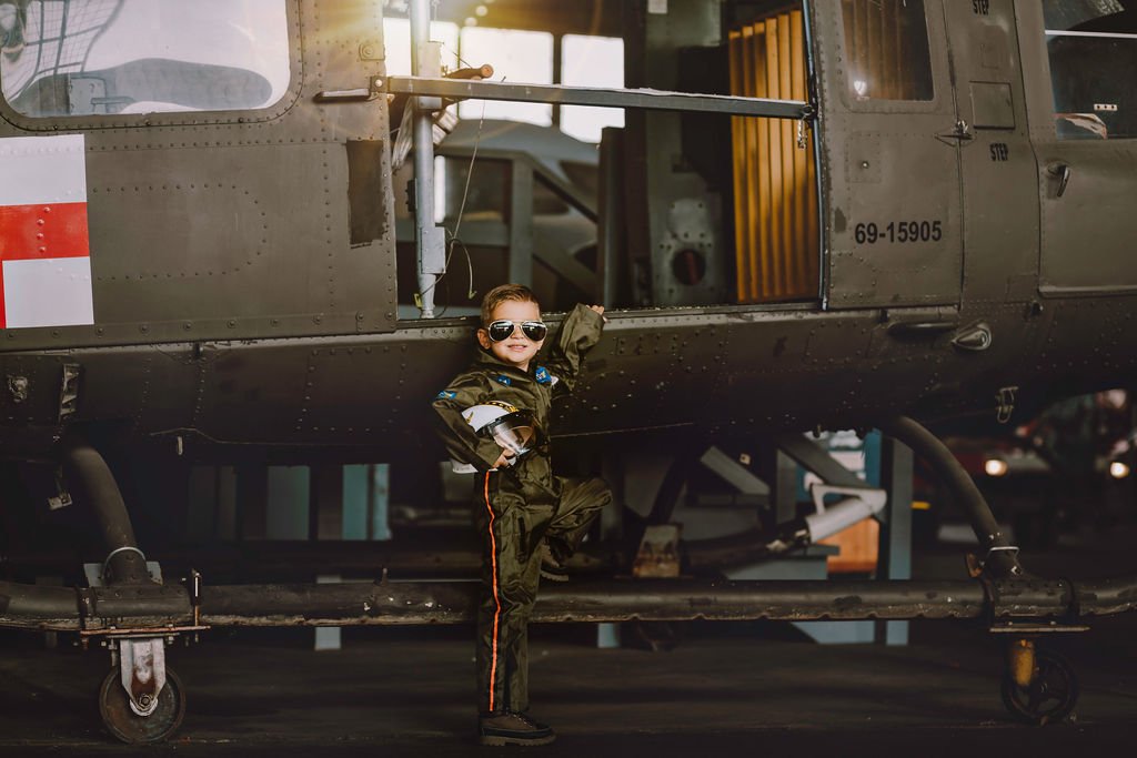 Smiling child wearing pilot helmet during aviation photoshoot by helicopter near Cape May New Jersey
