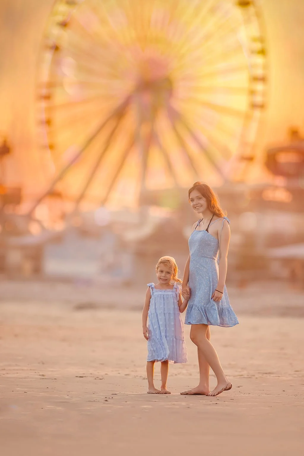 Two sisters smiling and holding hands in front of the Ferris wheel at Morey’s Pier in Wildwood NJ