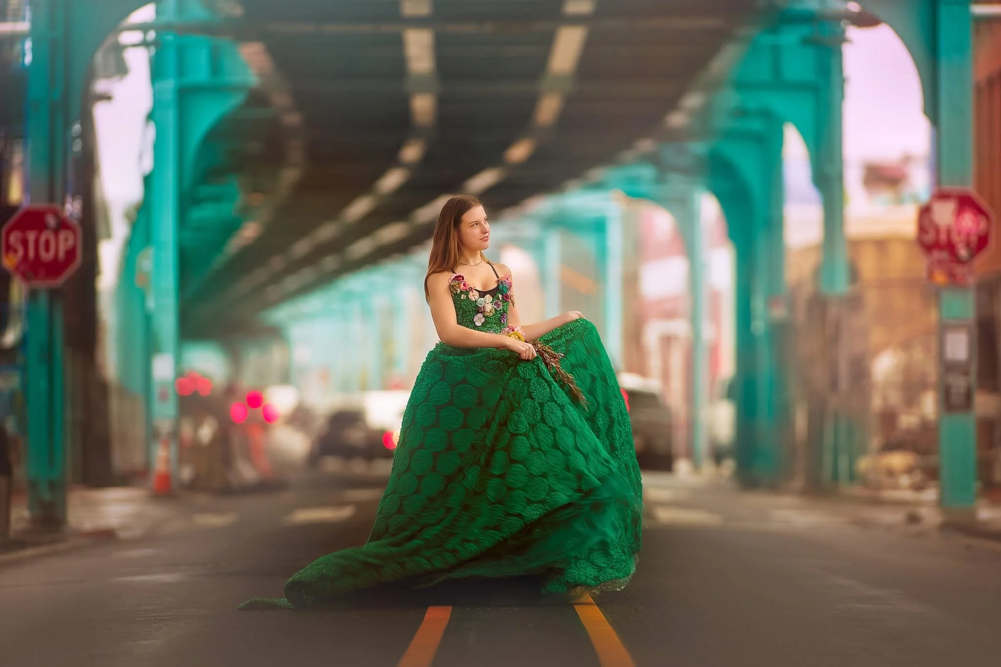 Teen girl in a flowing green dress photographed in an editorial-style fine art portrait with an urban backdrop.