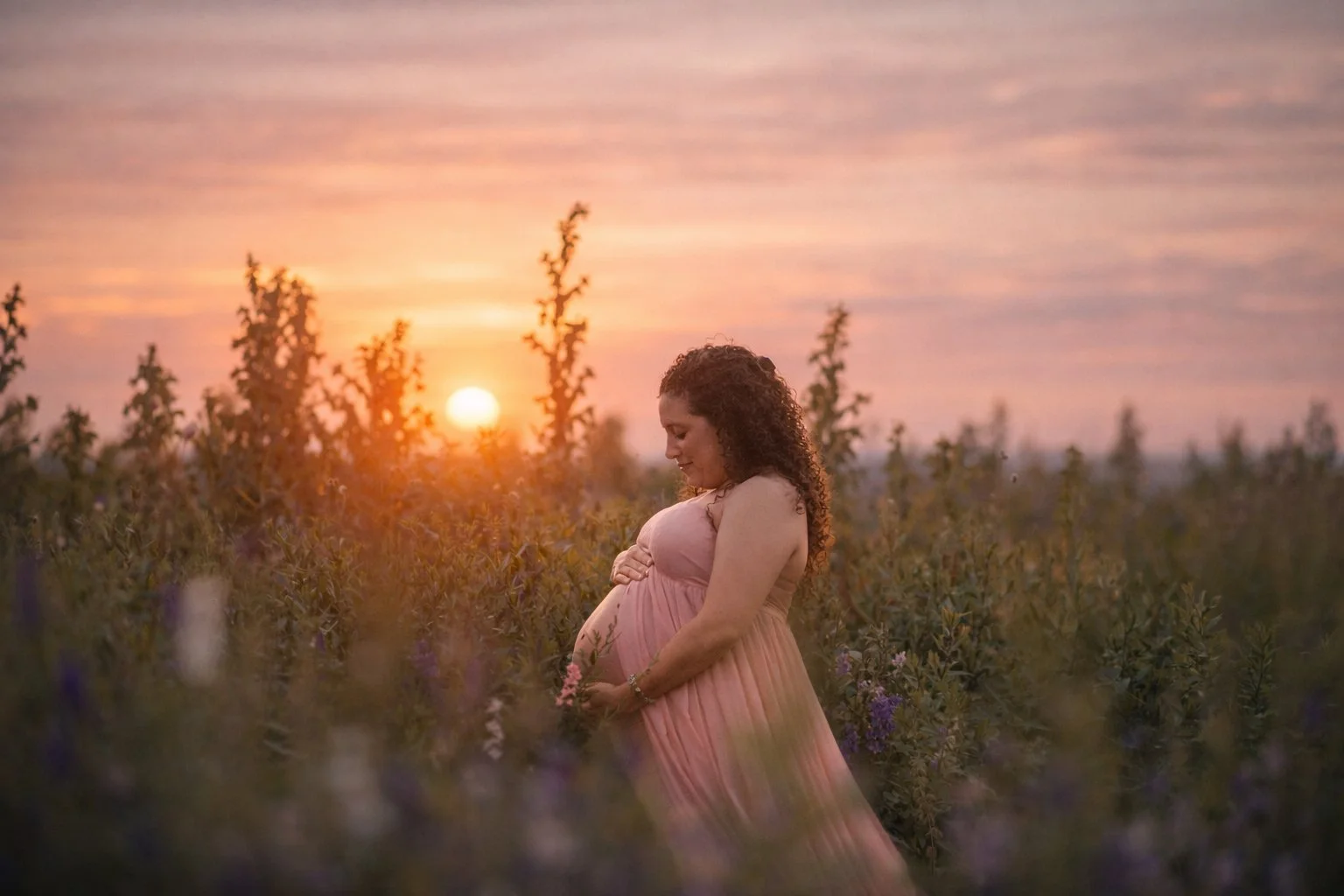 A maternity portrait captured in a wildflower field at sunset, showing that these seasonal sessions are perfect for families at every stage.