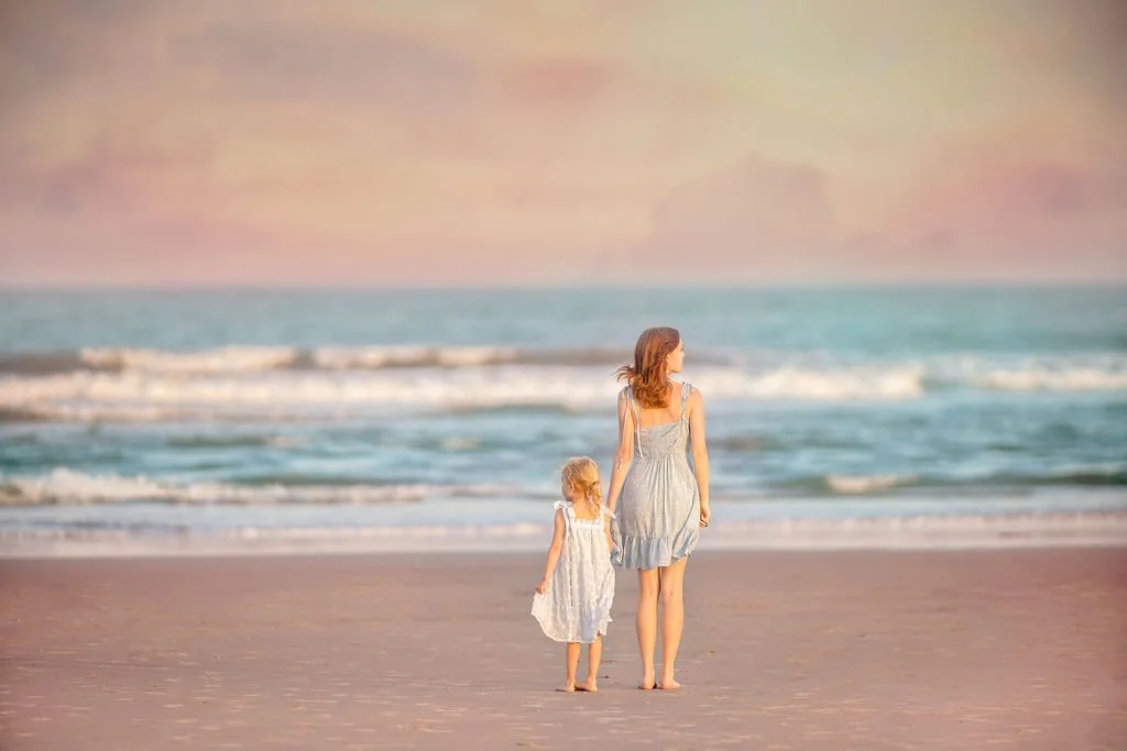 Two sisters holding hands and looking out at the ocean on the beach in Wildwood NJ