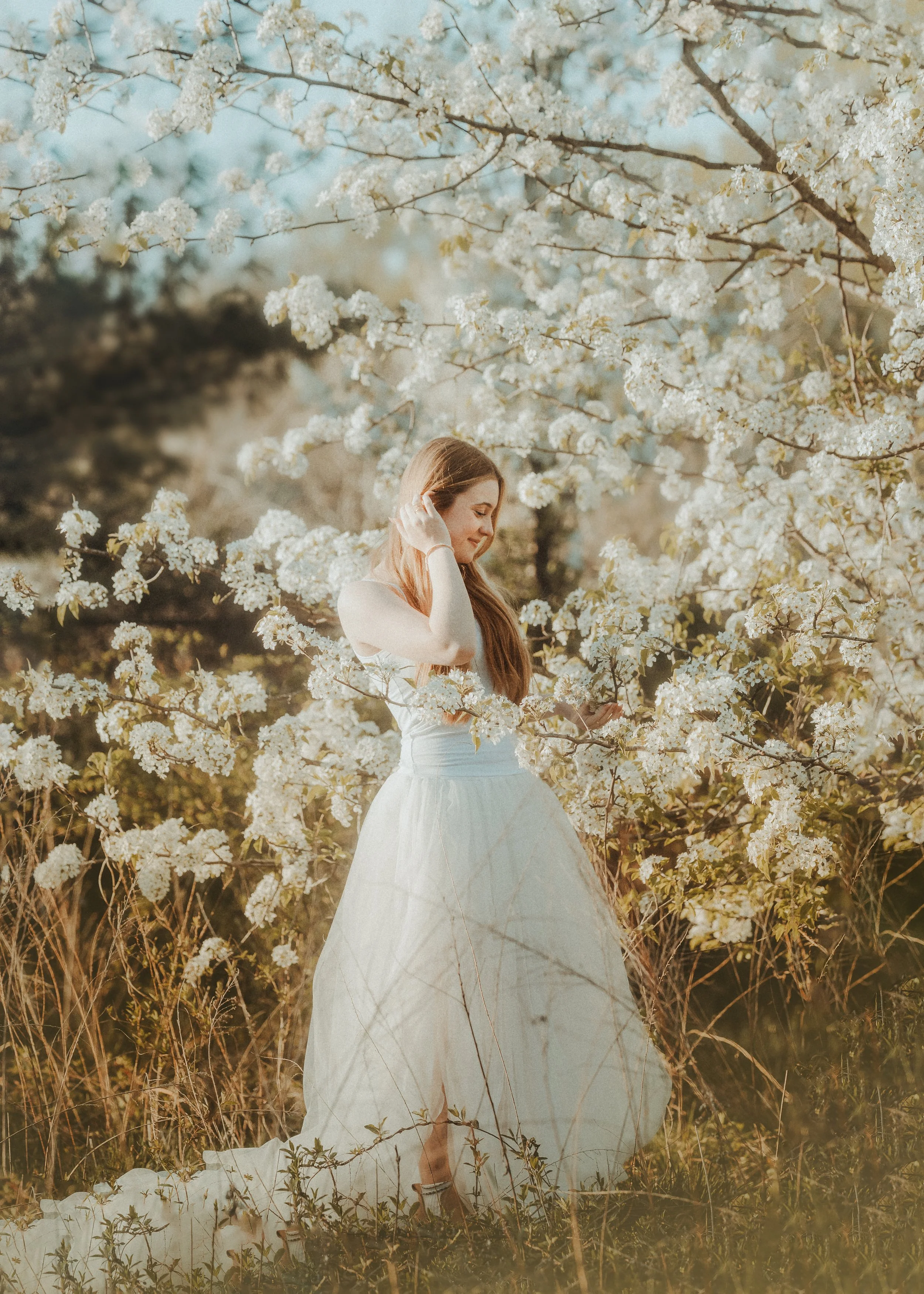 Senior portrait of a teen girl in blooming pear trees with soft spring light in New Jersey