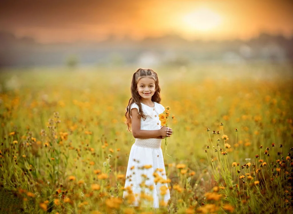 Young girl holding wildflowers during a sunset family maternity photography session in South Jersey