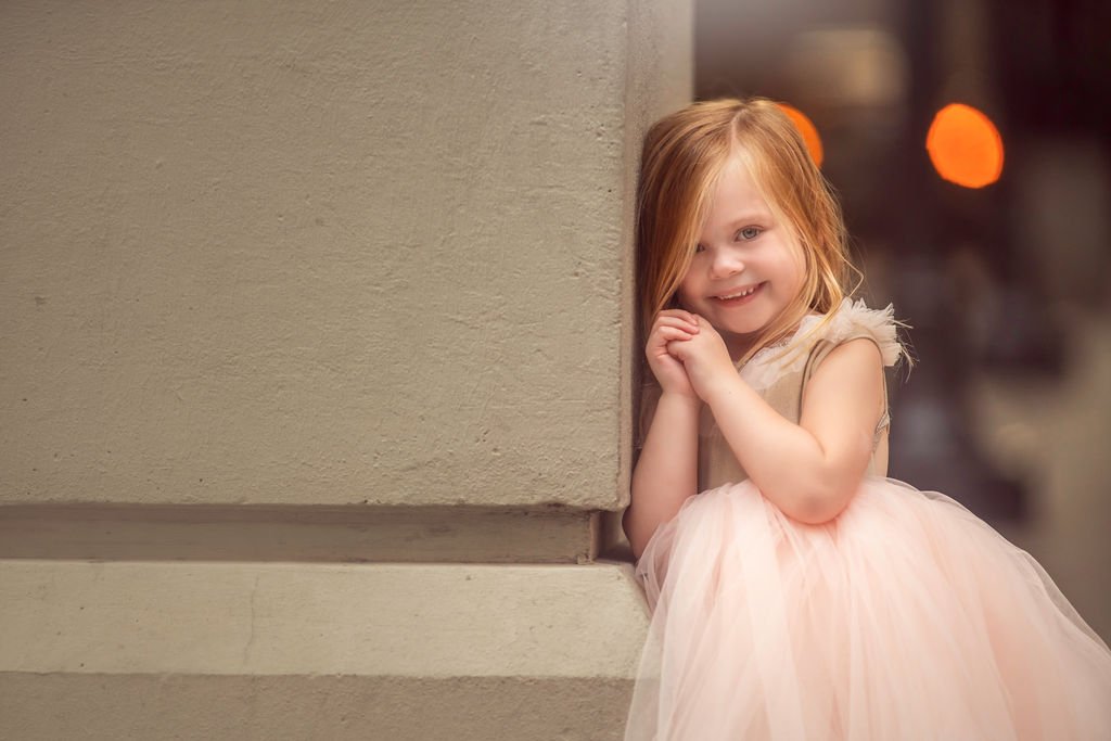 Girl smiling and looking at the camera on Broad Street in Philadelphia with City Hall behind her