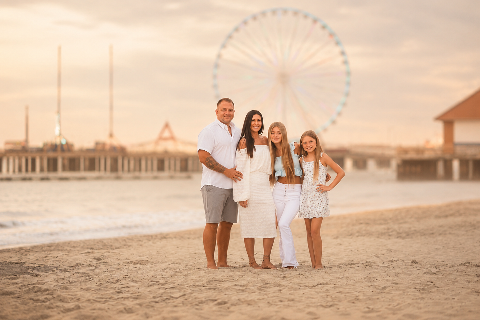 Family posing together on the beach with the Atlantic City pier and boardwalk in the background during a sunset photography session.