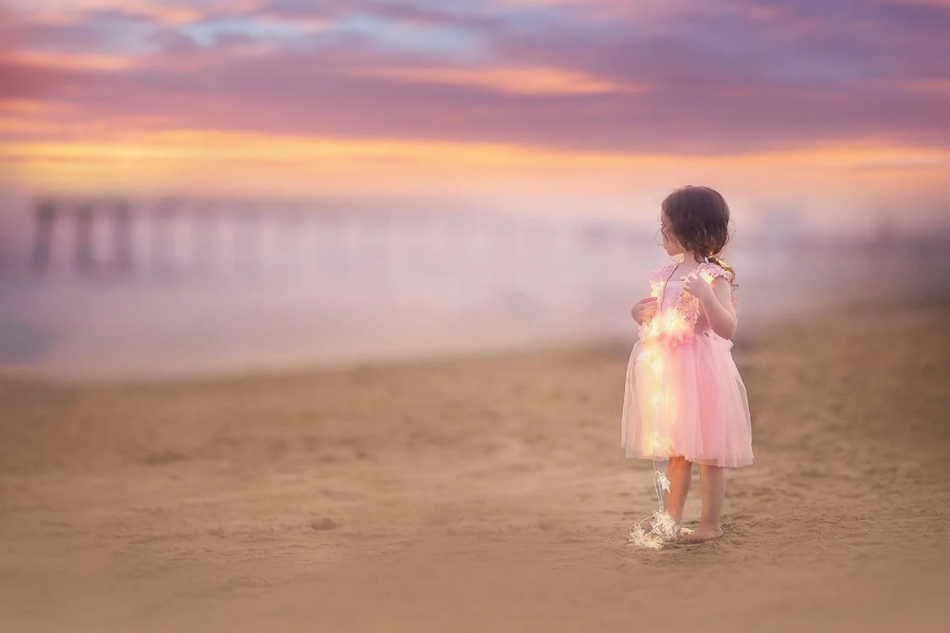 Joyful beach portrait of a young girl holding fairy lights by the fishing pier in Ocean City, NJ