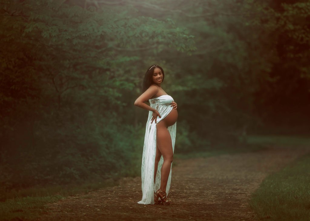Expectant mother holding her baby bump in a forest at Ridley Creek State Park during a maternity session