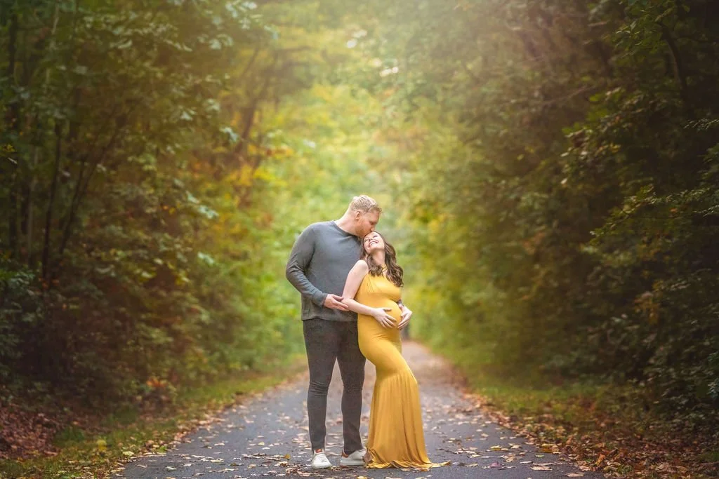 Father kissing pregnant mother on the forehead during a romantic outdoor maternity photography session in South Jersey.