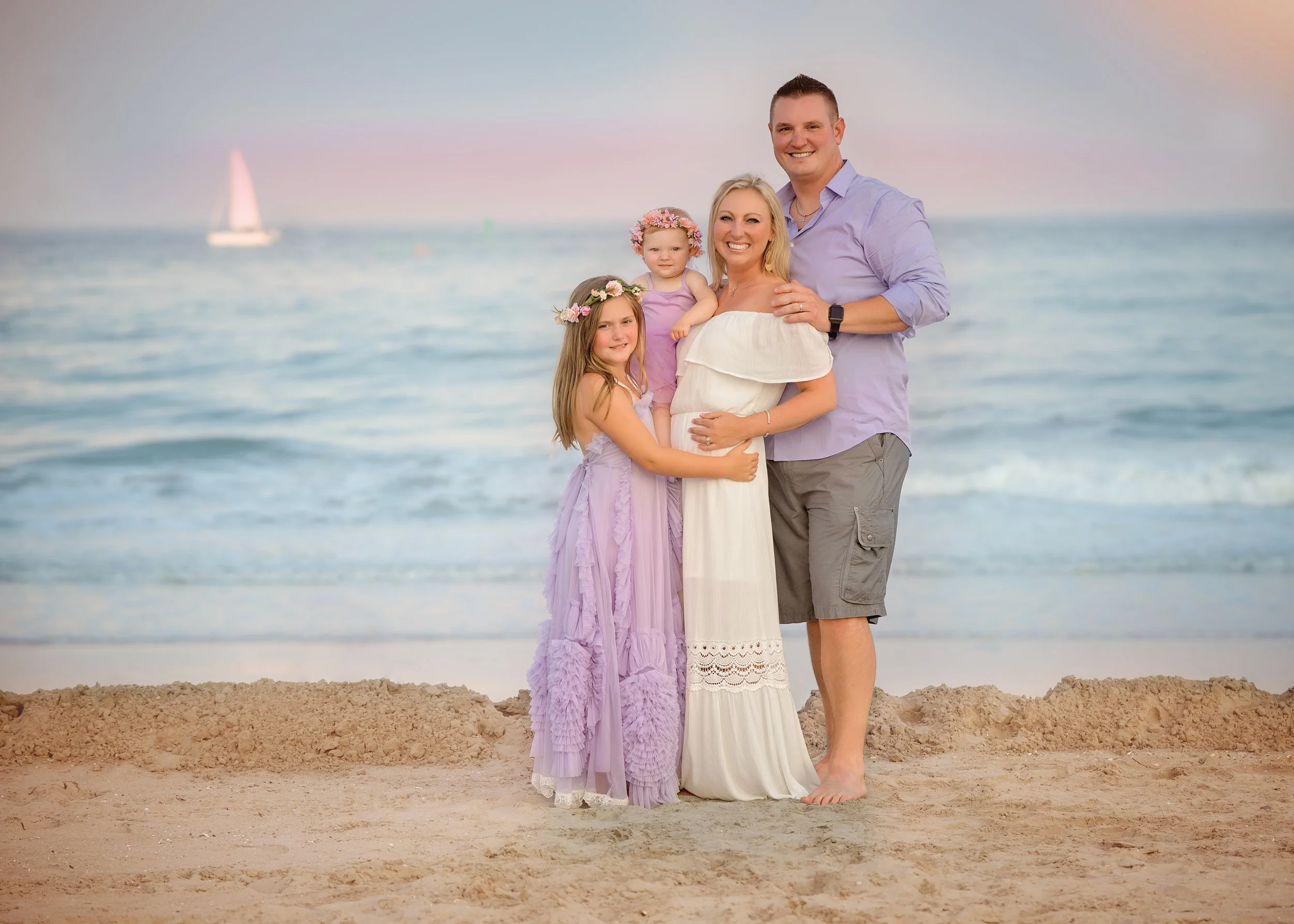 Family smiling together on the beach in Ocean City NJ during a natural light family portrait session.