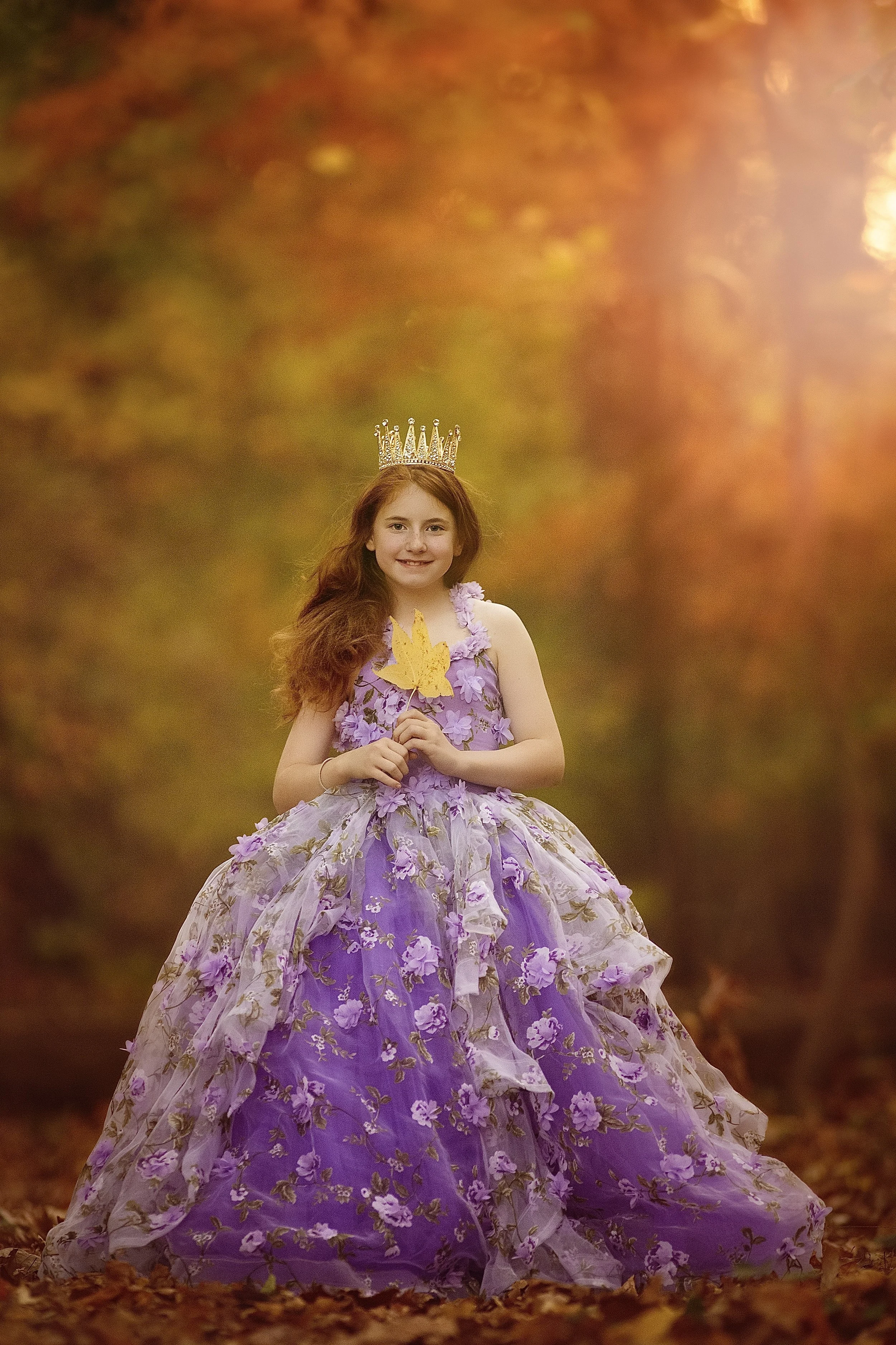 Girl in a purple dress holding a leaf during a fall portrait session near the Haddon Heights ball fields in South Jersey