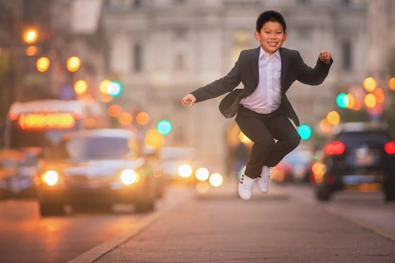 Young boy jumping on Broad Street in Philadelphia during a portrait session