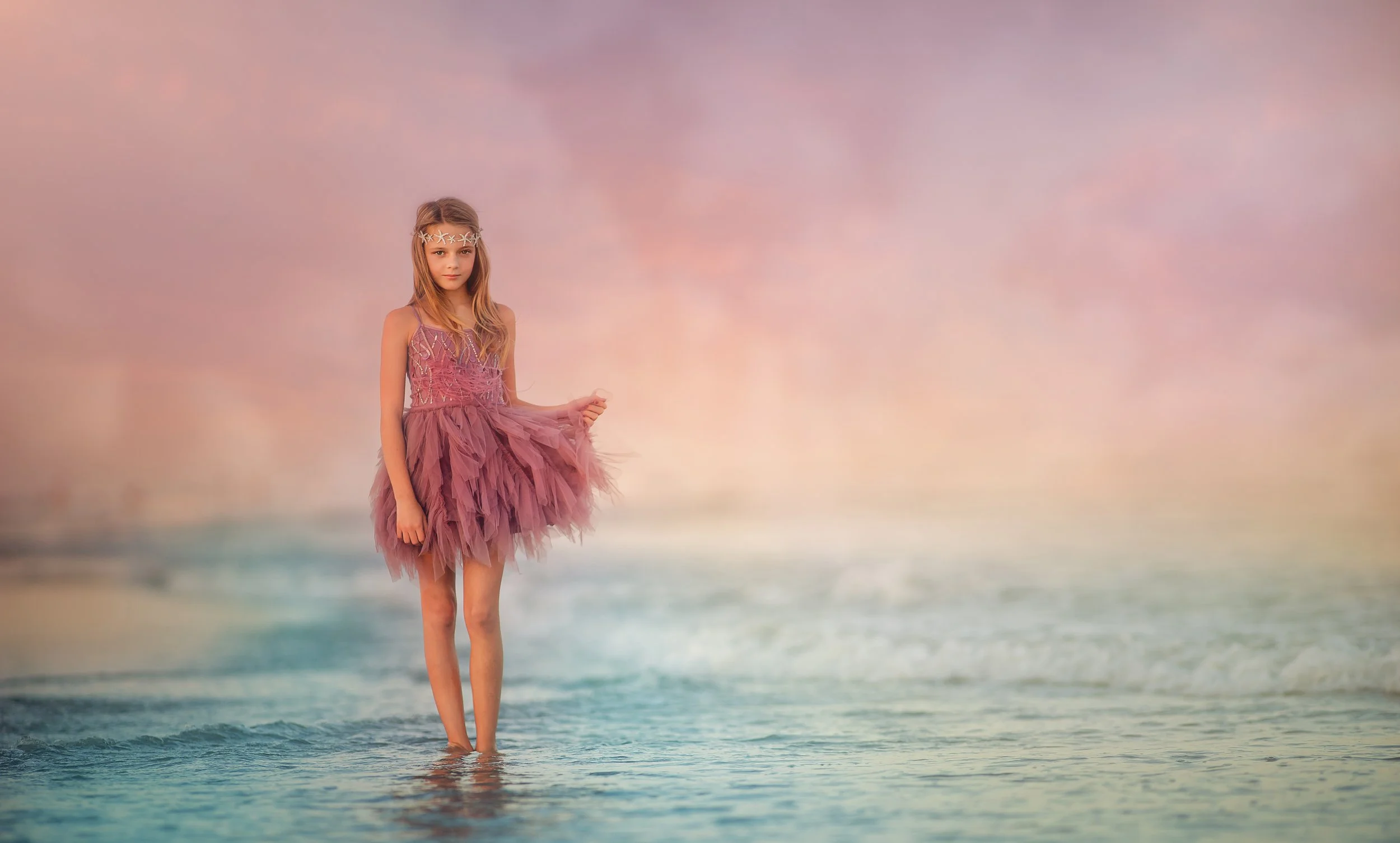 Girl standing in the ocean during sunset light on the beach in Wildwood New Jersey photographed by a Jersey Shore family photographer.