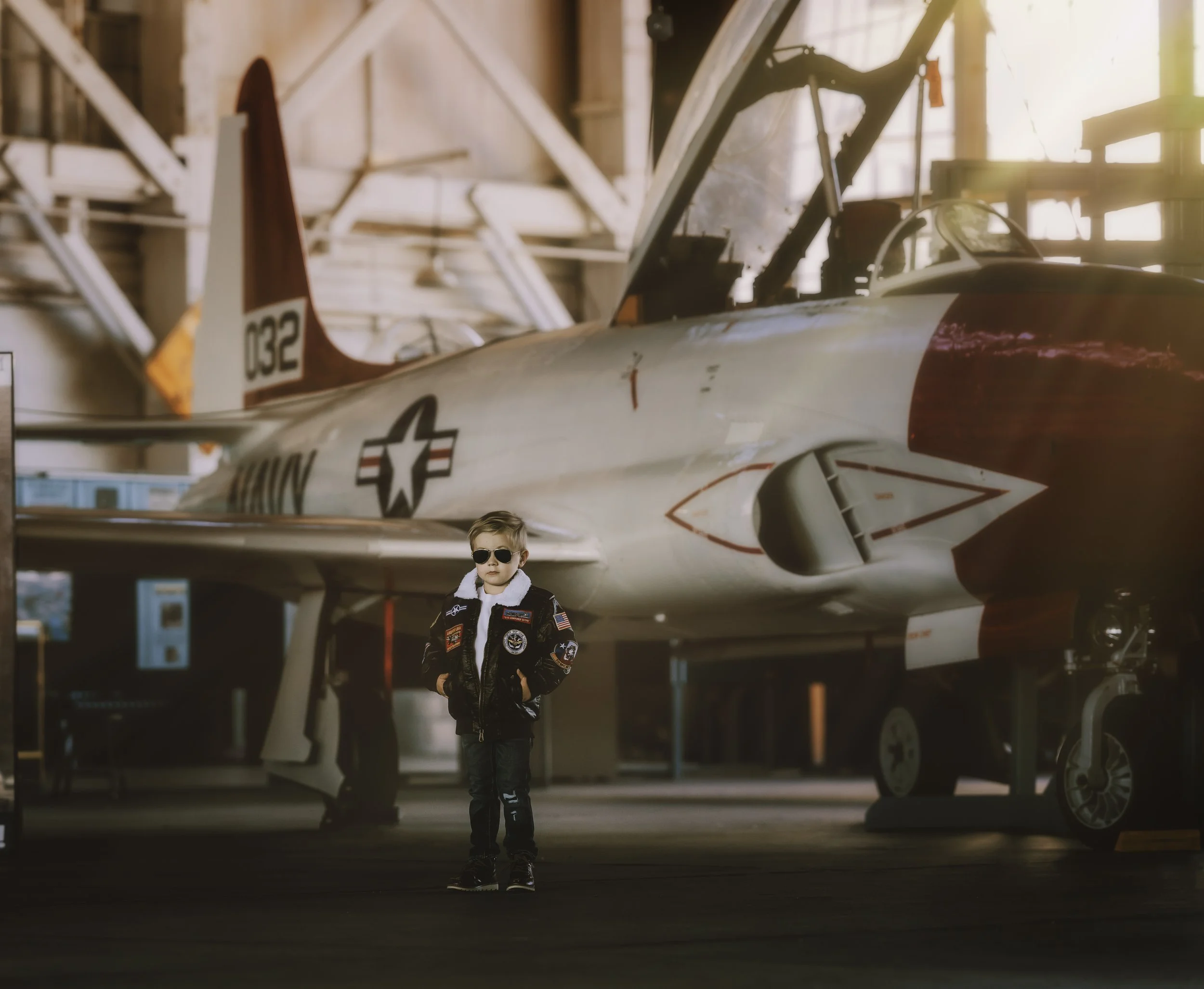 Child standing with hands in pockets in front of navy jet inside Naval Air Station Wildwood aviation museum New Jersey
