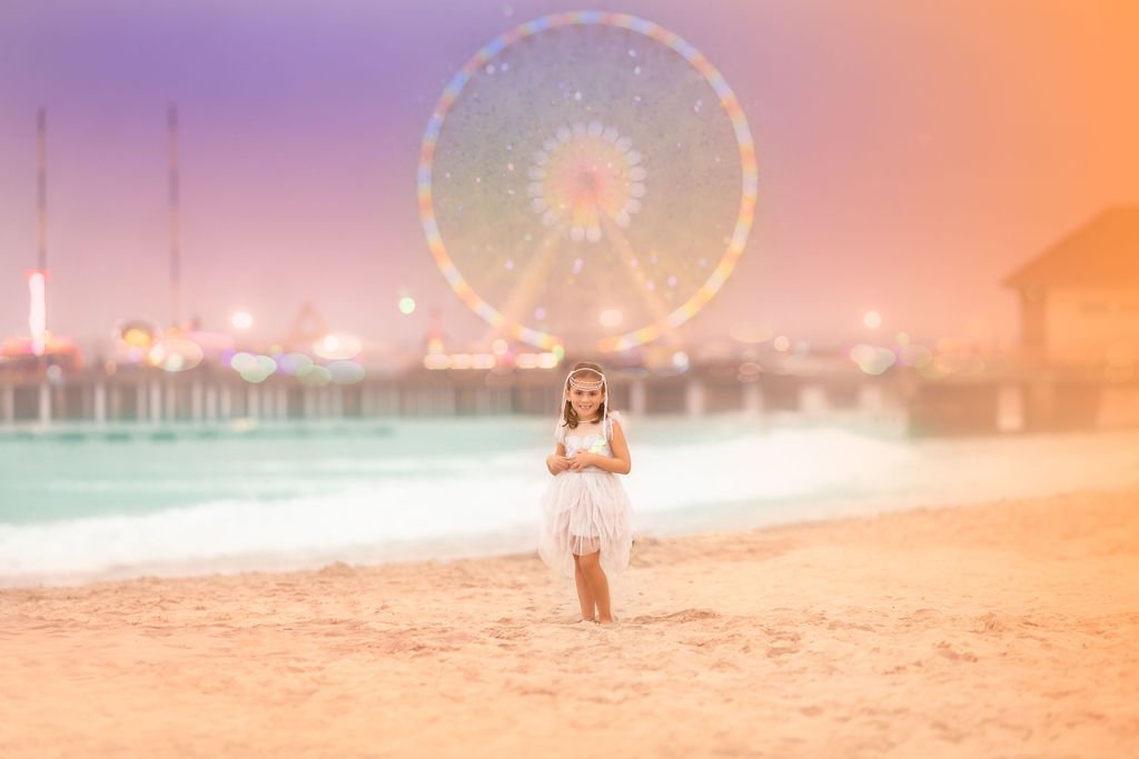 Young girl posing in front of a ferris wheel on the Atlantic City boardwalk during a Jersey Shore family photography session.