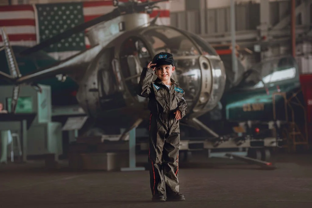 Boy tipping his hat while posing in front of helicopter during aviation photoshoot near Cape May New Jersey