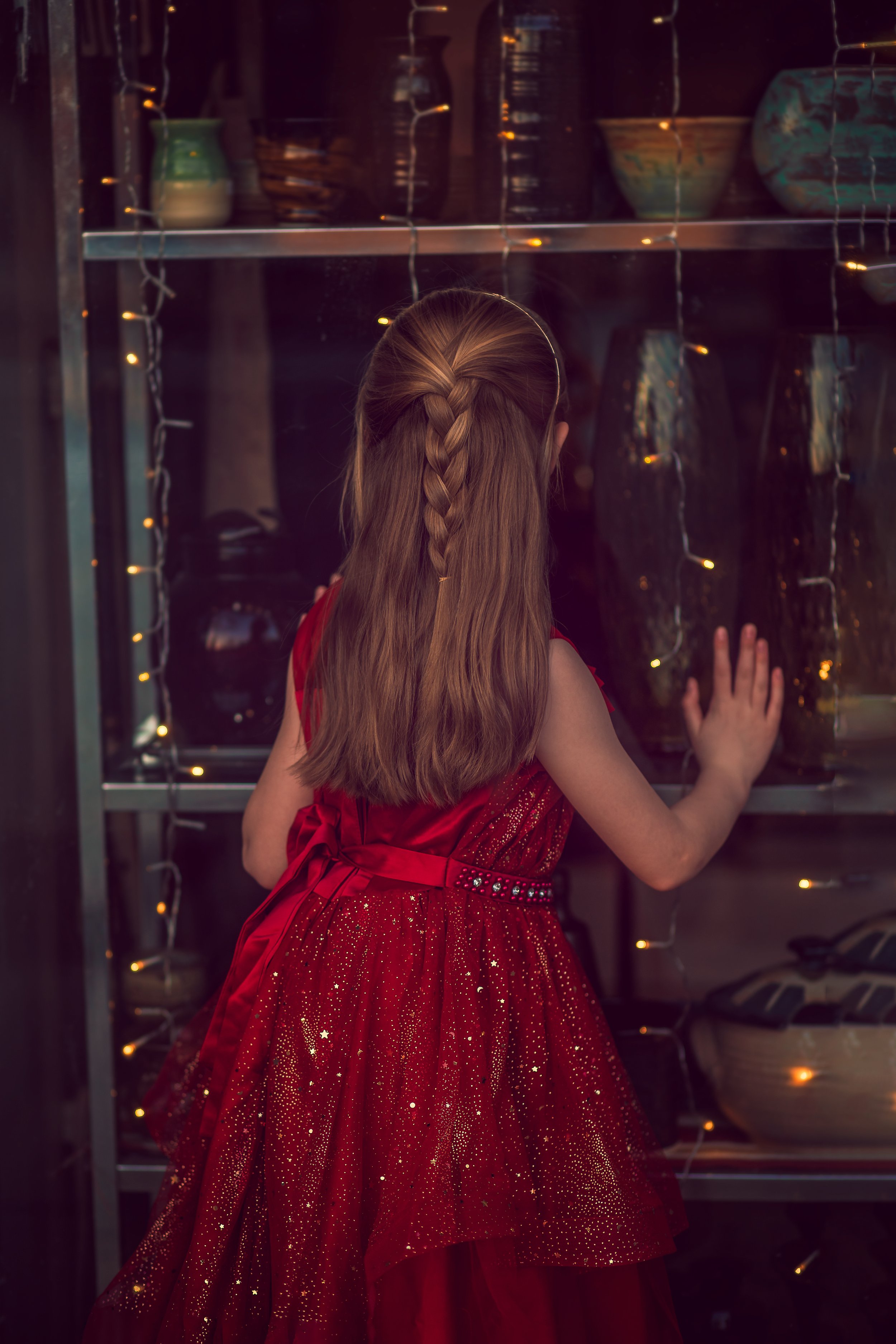 Child looking into shop window during downtown Collingswood NJ portrait session red dress detail