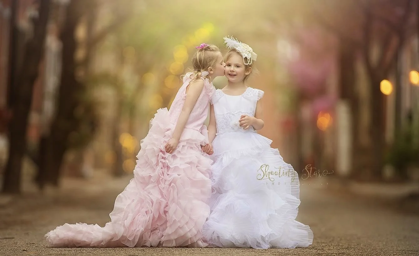 Sisters sharing a kiss on the cheek during a child portrait session in Philadelphia.