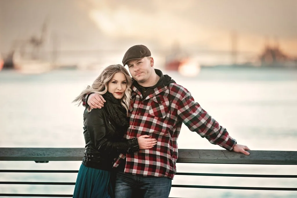 Engaged couple hugging during a winter engagement session at Race Street Pier with the Delaware River behind them