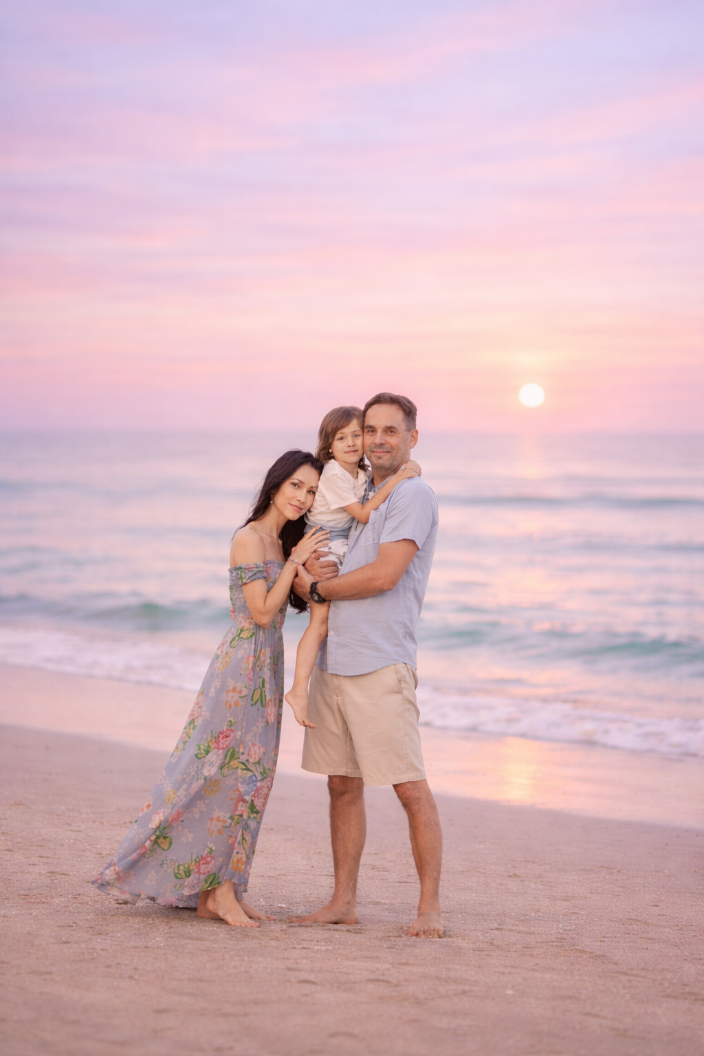 Family beach portrait in Cape May, New Jersey with mom, dad, and their young son walking together along the shoreline