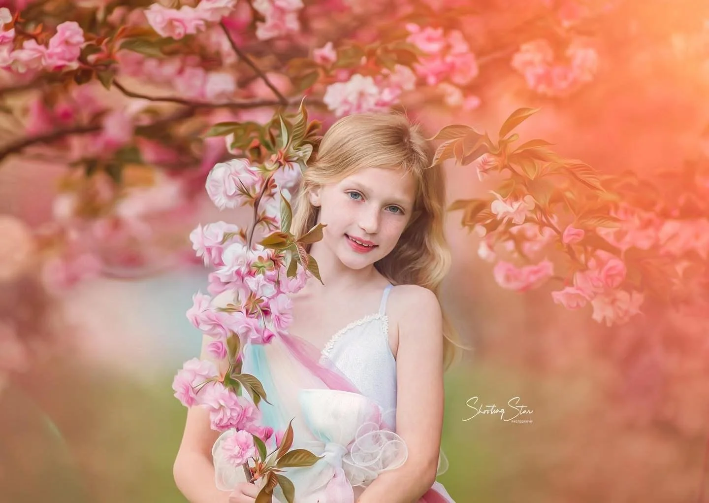Close-up portrait of a young girl in a blue dress beneath cherry blossoms in Cherry Hill, New Jersey.