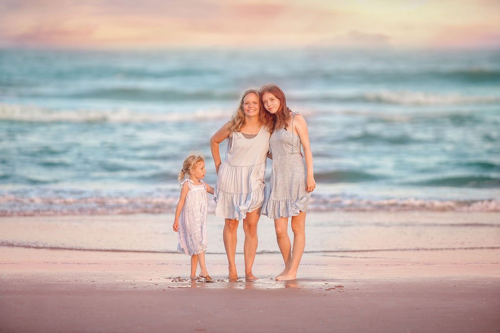 Mom with two daughters posing near the shoreline at Wildwood NJ beach during a family photo session