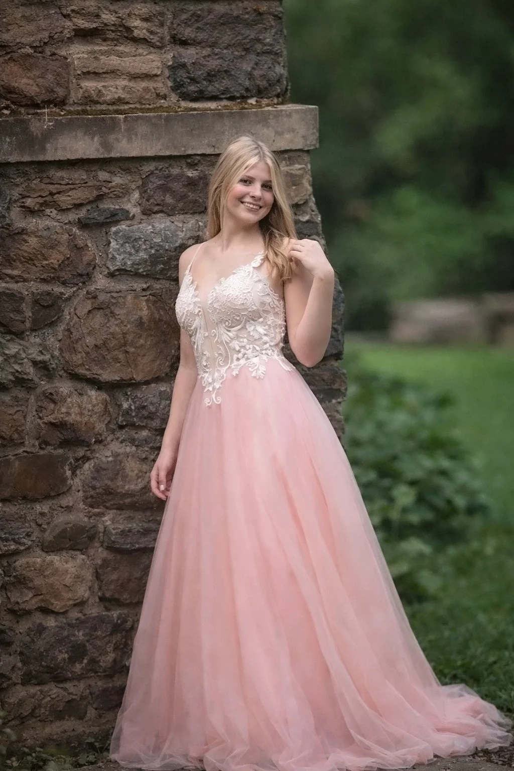 high school senior girl leaning against stone wall during relaxed senior photo session in South Jersey