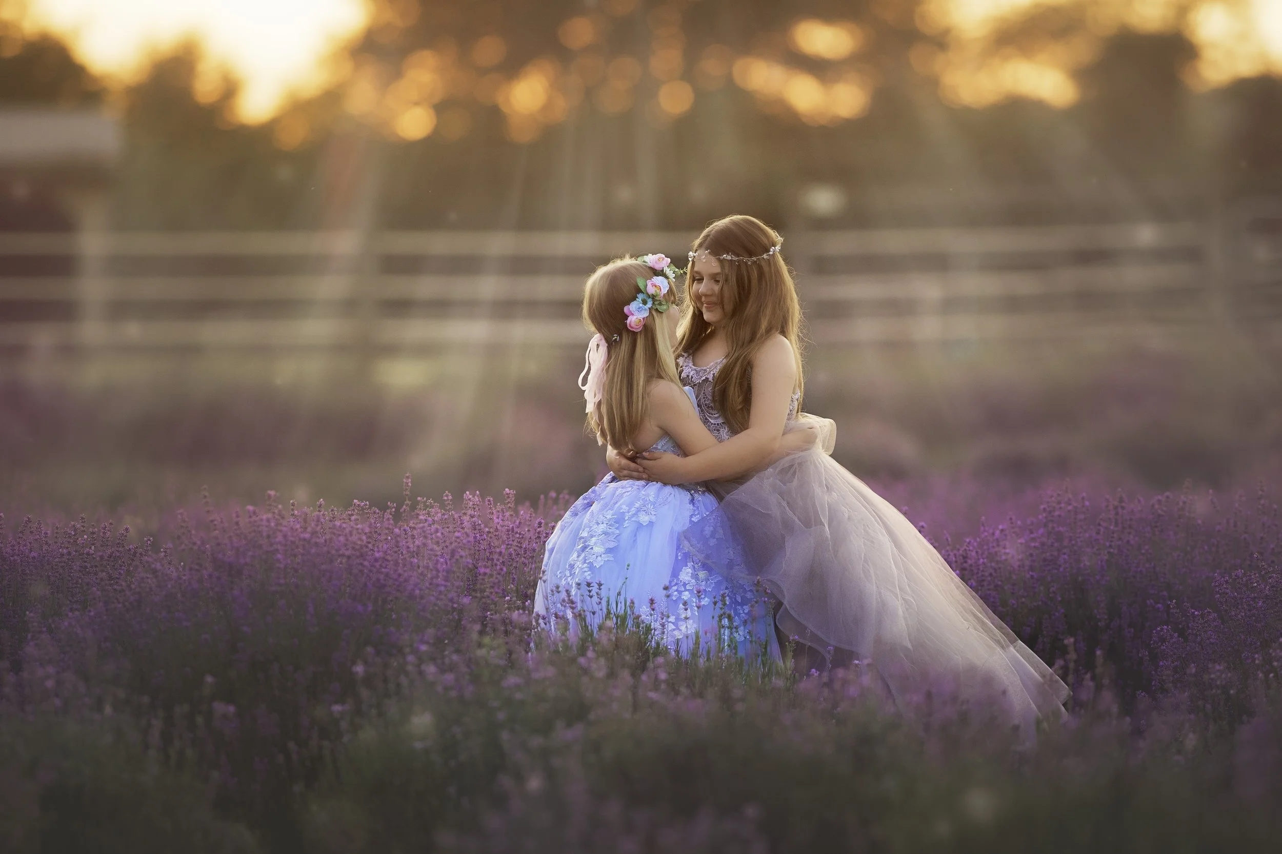 Two sisters embracing in a lavender field at sunset during a fine art child portrait session in South Jersey