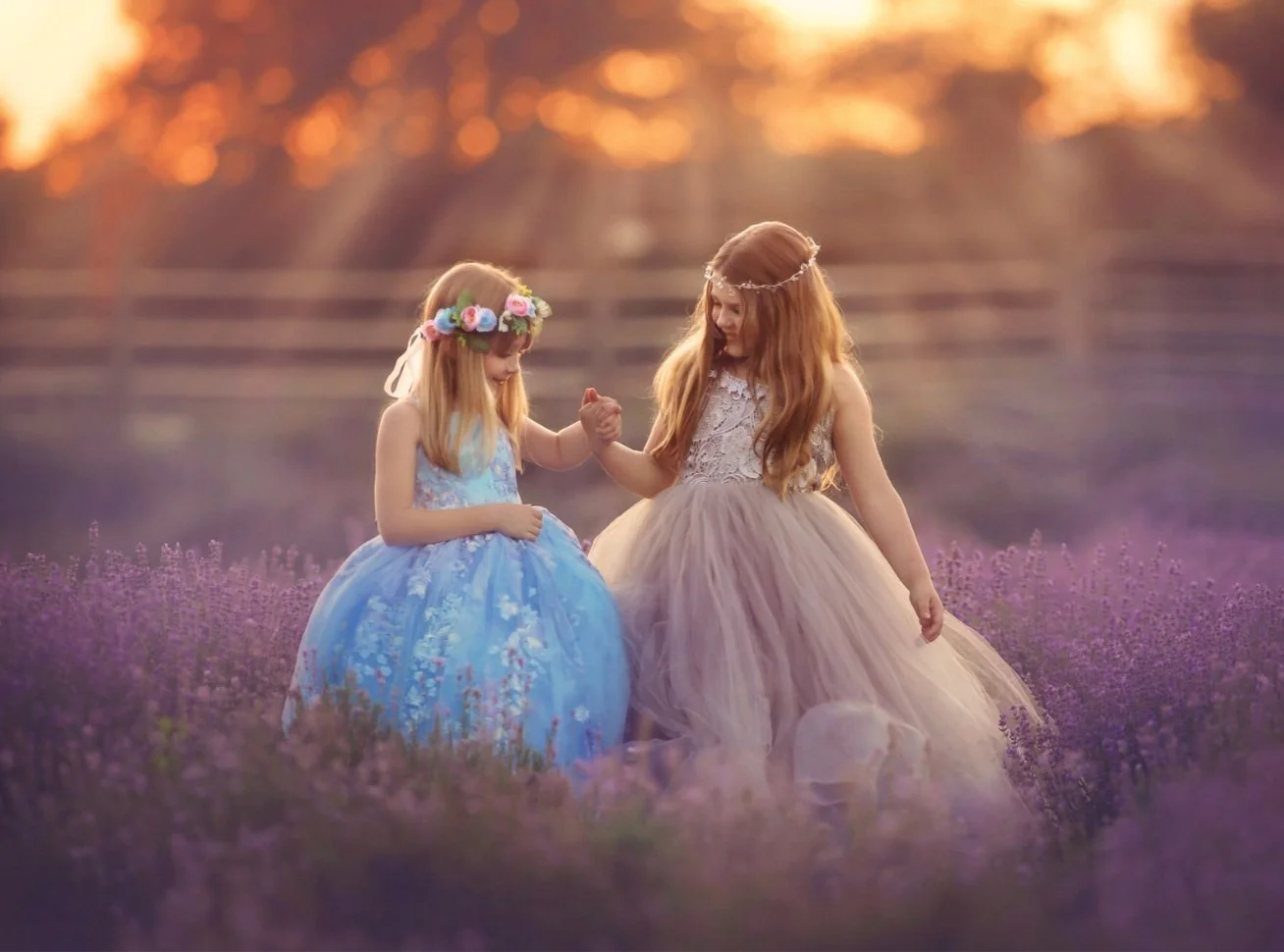 Two young girls walking together through a lavender field during a seasonal fine art children’s portrait session at sunset