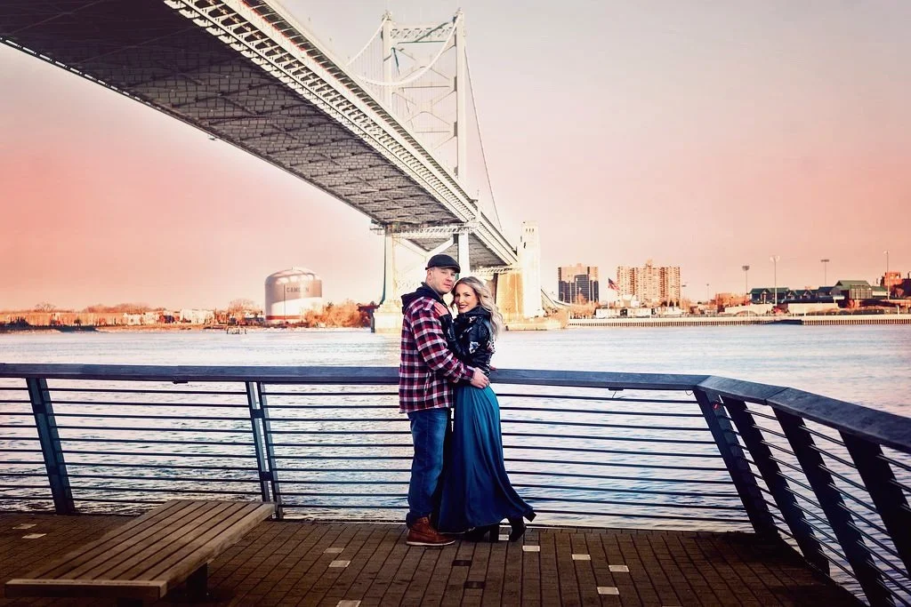 Engaged couple photographed at Race Street Pier with the Benjamin Franklin Bridge in the background