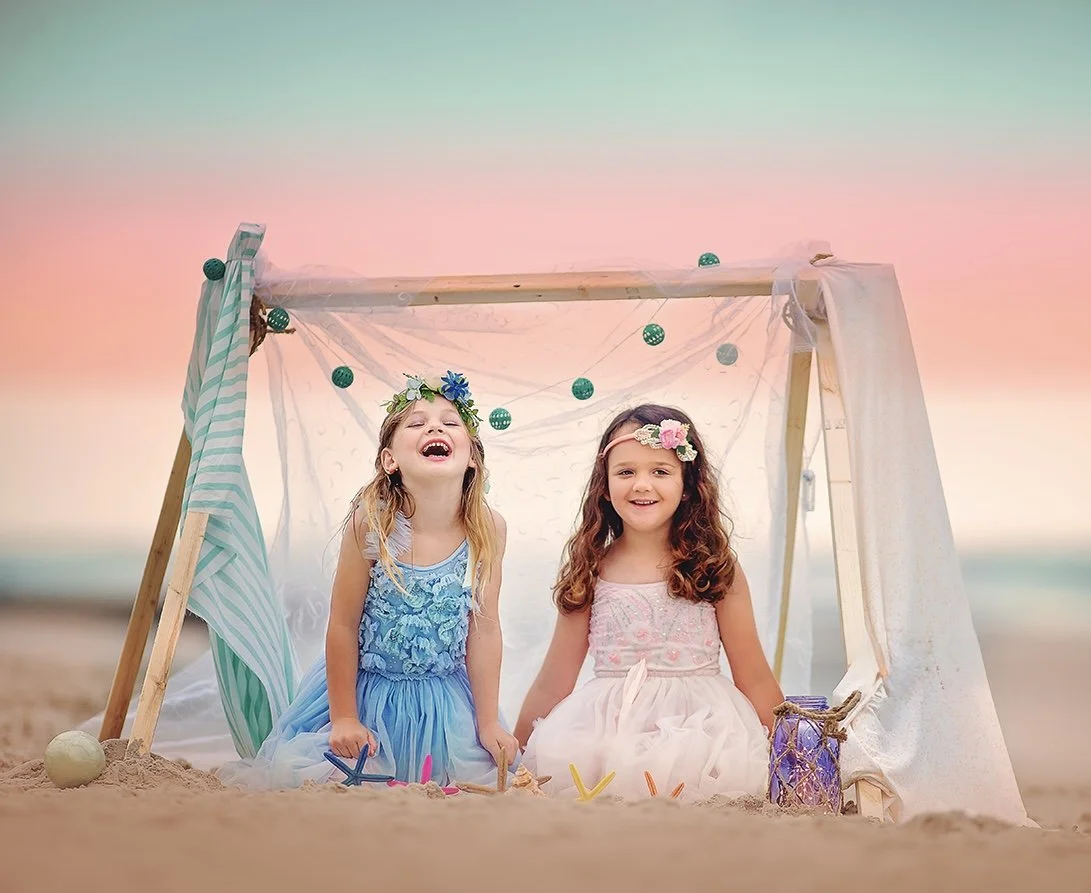 Two girls laughing together on the beach during a family photography session in Ocean City NJ