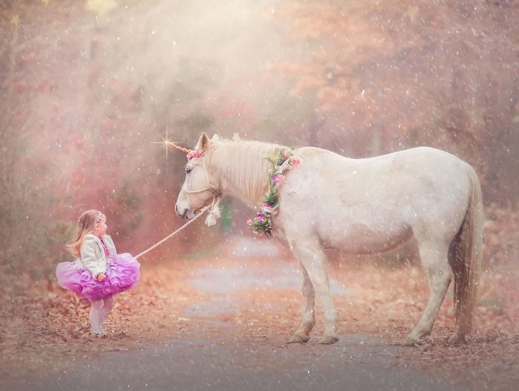 young girl walking a unicorn through a forest during a magical portrait session in New Jersey
