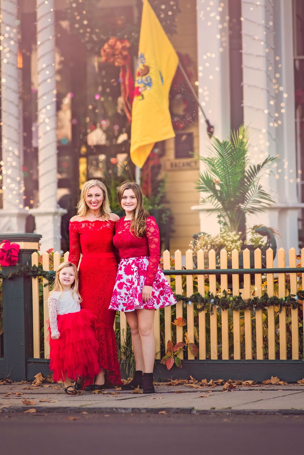 Mother and two daughters posing in front of a historic bed and breakfast in Cape May New Jersey during a family portrait session photographed by a Jersey Shore family photographer.