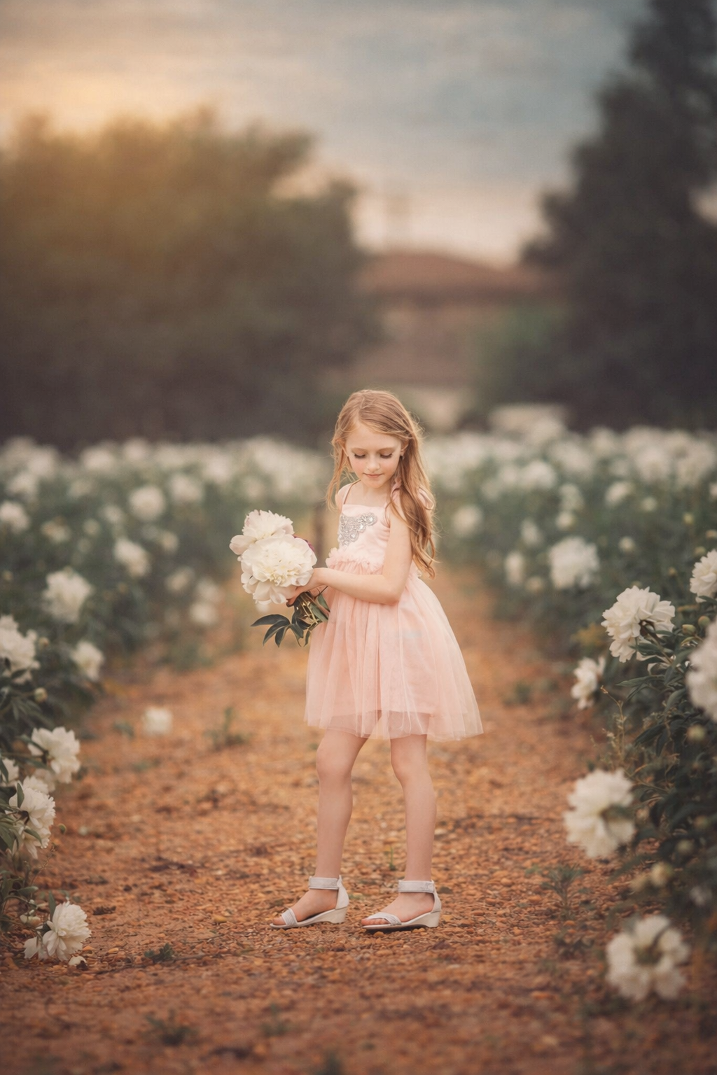 A young girl in a pink dress holding a peony, photographed in soft natural light for a timeless fine art children’s portrait.