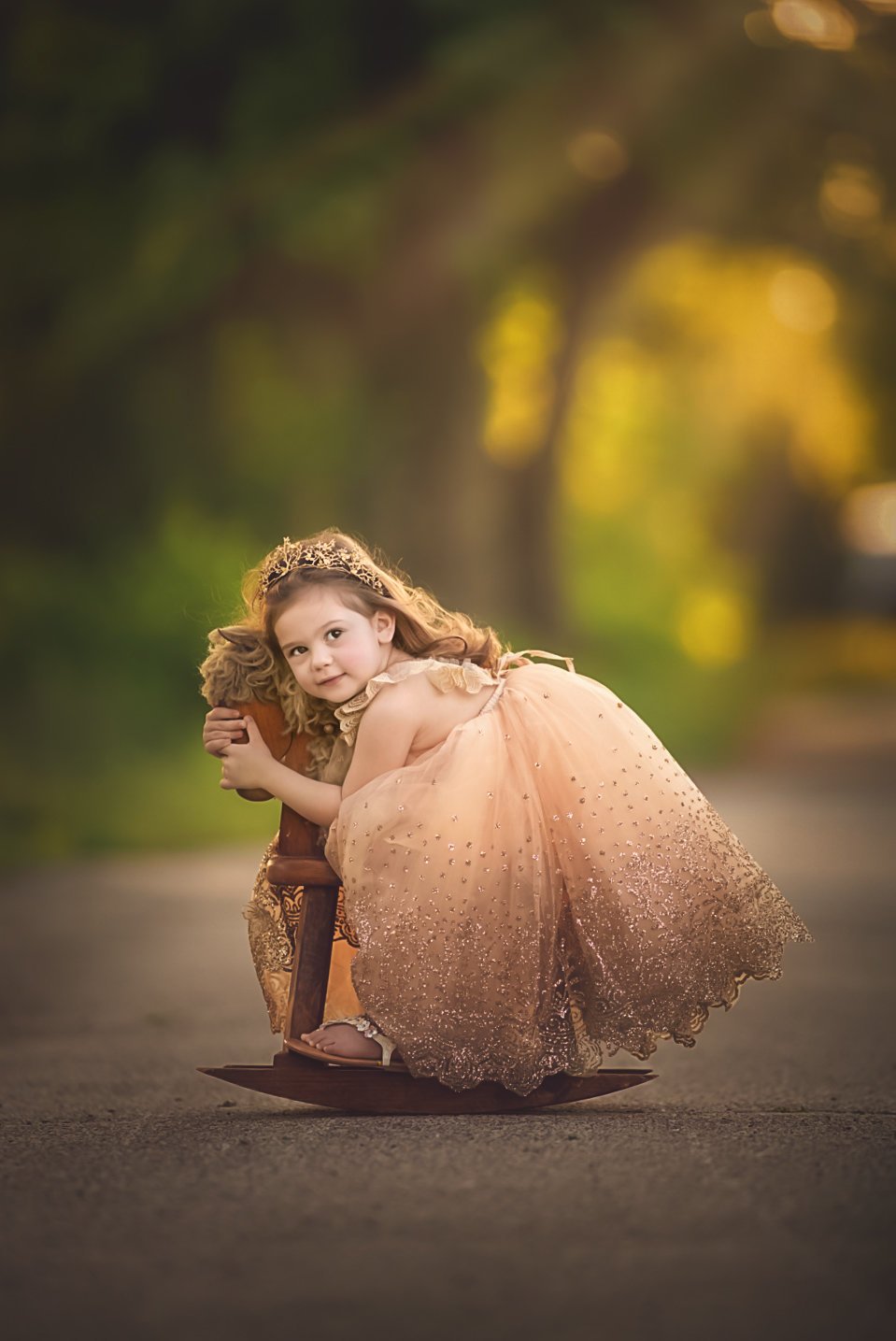 toddler girl sitting on rocking horse during outdoor portrait session in Sewell NJ