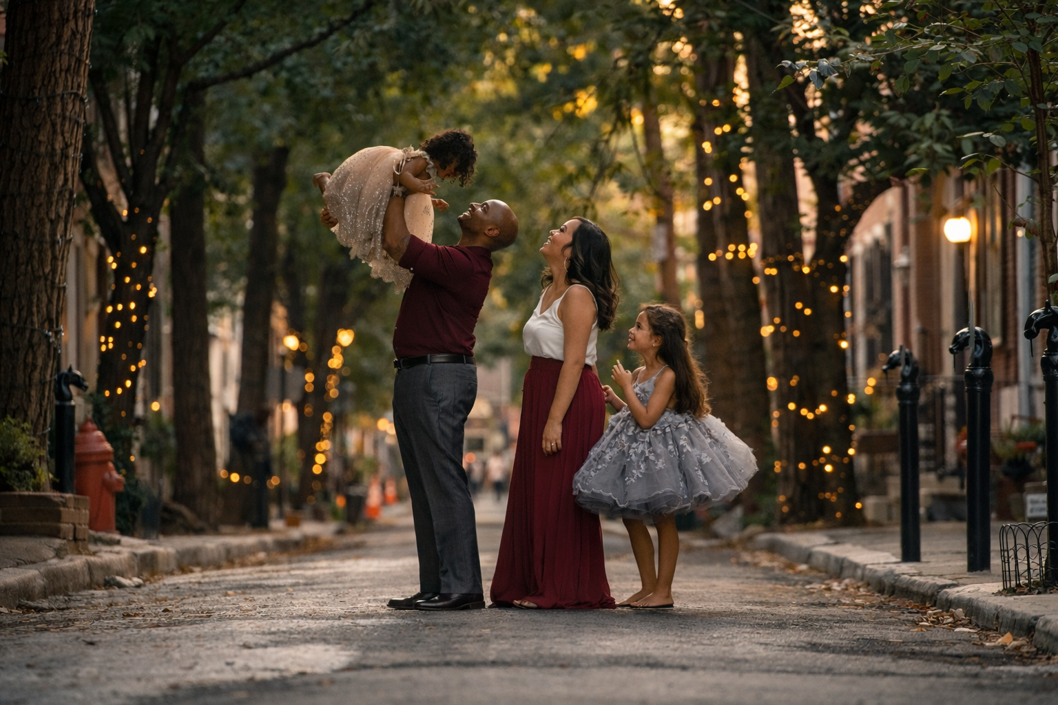 family portrait on addison street in Philadelphia, whole family in a beautiful moment with the lights on the trees sparkling behind them